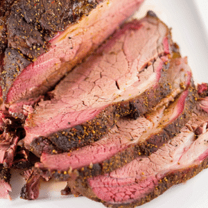 smoked corned beef brisket sliced on cutting board in backyard