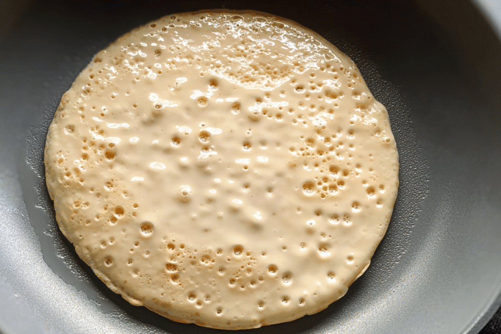 Vegan Protein Pancakes: Fluffy, Filling, and Plant-Powered Every Time 10 Vegan protein pancake cooking in a skillet with bubbles